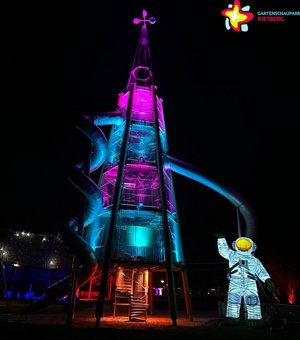 Astronautenfigur vor dem bunt beleuchteten Rutschenturm.