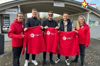 Mitarbeiter und Sponsoren mit der neuen Dienstkleidung vor dem Eingang Nord.