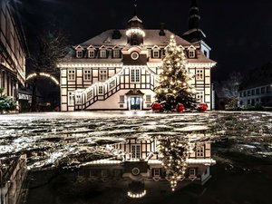 Rietberger Rathaus mit Weihnachtsbaum davor spiegelt sich in einer Pfütze.