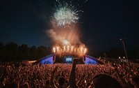 Die Volksbank-Arena mit Feuerwerk über dem Dach, im Vordergrund tanzen die Besucher.