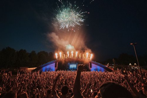 Die Volksbank-Arena mit Feuerwerk über dem Dach, im Vordergrund tanzen die Besucher.
