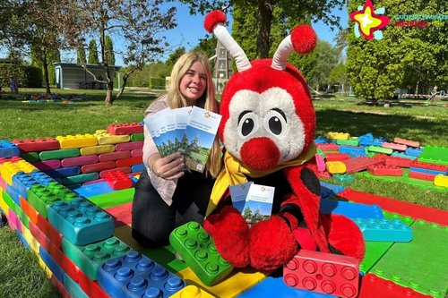 Mskottchen Rieti und Gartenschaupark-Mitarbeiterin Bianca Piekatz inmitten der Großbausteine mit den neuen Flyern.
