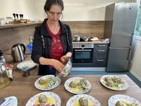 Anke Langenbach befüllt die Teller in der "Wilden Kräuterküche" mit den gerade gebrutzelten Leckereien.
