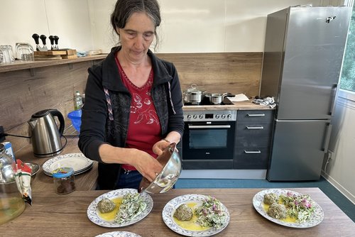Anke Langenbach befüllt die Teller in der "Wilden Kräuterküche" mit den gerade gebrutzelten Leckereien.