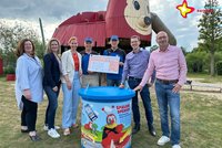 Spender und Gartenschaupark-Vertreter stehen vor der Rieti-Rutsche, die Boule-Vertreter haben einen Scheck in der Hand. Im Vordergrund ist der neue Spendentrichter zu sehen.