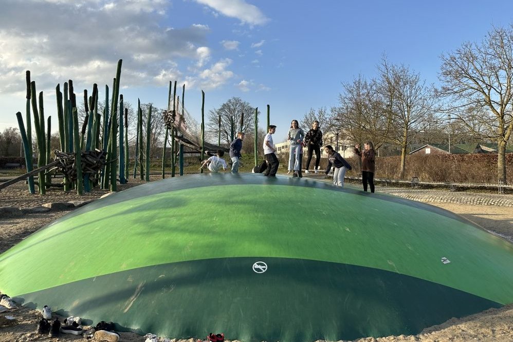 Kinder hüpfen auf dem grünen Hüpfkissen im Parkteil Mitte.