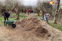 Zu sehen sind Helfer, die Rindenmulch in Schubkarren schaufeln und verteilen. Im Hintergrund sind die Hexenhäuschen zu sehen.