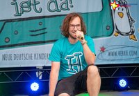 herrH hockt auf der Bühne, das Mikro vor dem Mund.