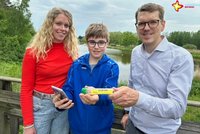 Luca Spratte, Laura Hunke und Johannes Wiethoff mit einem kleinen Kunststoffröhrchen, das beim Geocaching gefunden werden muss.