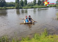 Zu sehen ist ein Kanu mit zwei Menschen, die sich mit Paddeln vom Ufer abstoßen.