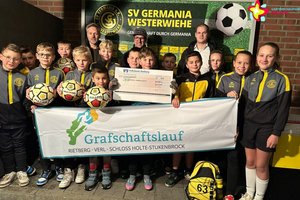 Nachwuchssportler, Jugendleiter, Sponsor und Oragnisator vor einer großen Wand mit SV-Germania-Westerwiehe-Schriftzug.