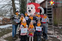 Sieben Erwachsene und drei Kinder stehen vor einer traurig ausschauenden Rieti-Figur. In den Händen halten sie Bilder aus dem Malwettbwerb, bei dem Kinder zeichnen konnten, wie sie sich eine neue Rieti-Rutsche vorstellen.