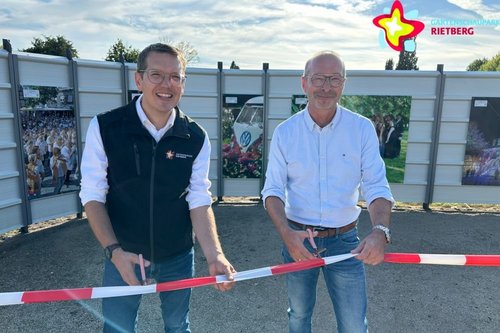Johannes Wiethoff und Frank Ehlebracht schneiden das Band durch. Im Hintergrund sind mehrere große Fotos zu sehen.
