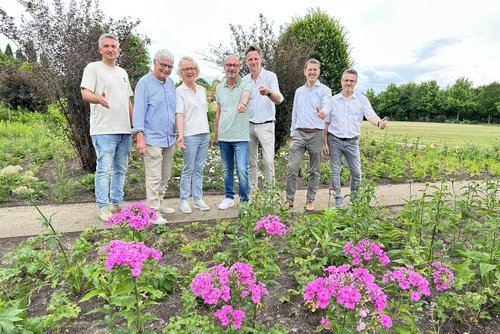 Die genannten Personen stehen auf einem Kiesweg, davor ist die Staudengalerie zu sehen.