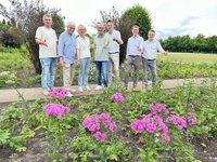 Die genannten Personen stehen auf einem Kiesweg, davor ist die Staudengalerie zu sehen.