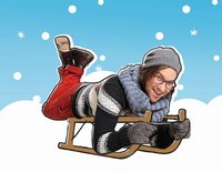 Kinderliedermacher herrH, winterlich gekleidet, liegt auf dem Bauch auf einem Schlitten.