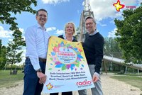 Johannes Wiethoff, Meike Wellemeyer und Carsten Schoßmeier mit dem Radio-Gütersloh-Sommerfest-Plakat vor dem großen Rutschenturm.