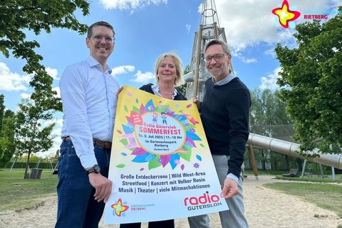 Johannes Wiethoff, Meike Wellemeyer und Carsten Schoßmeier mit dem Radio-Gütersloh-Sommerfest-Plakat vor dem großen Rutschenturm.