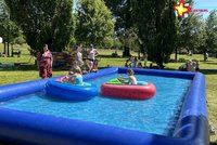 Zu sehen ist ein Wasserbecken, auf dem Kinder in zwei kleinen Booten unterwegs sind.