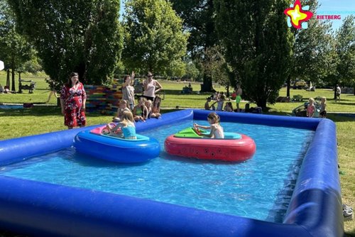 Zu sehen ist ein Wasserbecken, auf dem Kinder in zwei kleinen Booten unterwegs sind.