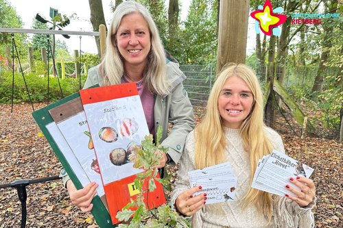 Andrea Sassenberg (links) und Bianca Piekatz mit Schautafeln und Rätselkarten auf einem Spielplatz.