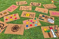 Bunt gestaltete Fußmatten liegen auf einer Wiese.