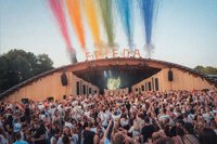 Blick auf die Hauptbühne bei Friedas Tanztee, die Volksbank-Arena. Im Vordergrund feiernde Menschen. Über den F-R-I-E-D-A-Buchstaben auf dem Dach der Arena bunte Fontänen.