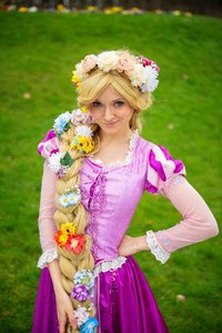 Eine als Rapunzel verkleidete junge Dame auf einer Wiese.