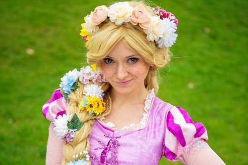 Eine als Rapunzel verkleidete junge Dame auf einer Wiese.