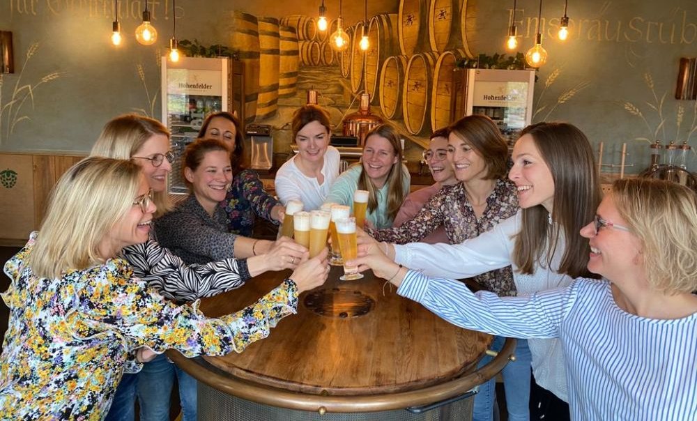 Eine Gruppe junger Damen stößt mit Biergläsern an.