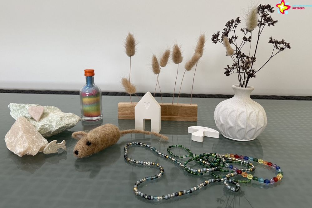 Gebasteltes aus Gips, Holz und anderen Materialien. Zu sehen sind eine Vase, eine Perlenkette, kleine Häuschen und mehr.