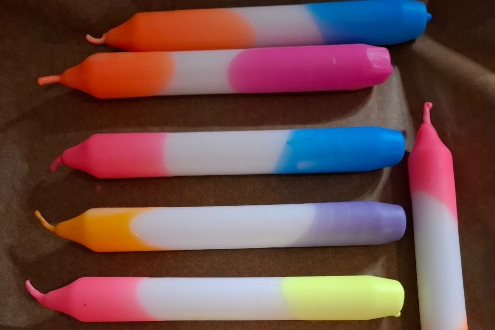 Zu sehen sind Kerzen, die an den beiden Enden jeweils unterschiedliche Farben haben als in der Mitte.