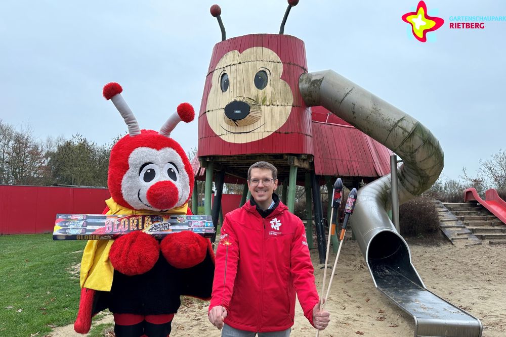 Johannes Wiethoff und Maskottchen Rieti stehen mit Raketen und Wunderkerzen in der Hand vor der Rieti-Rutsche, die erneuert werden soll.
