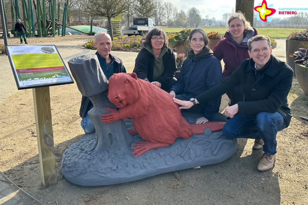 Künstler und Organisatoren hocken rund um den knallroten Biber.