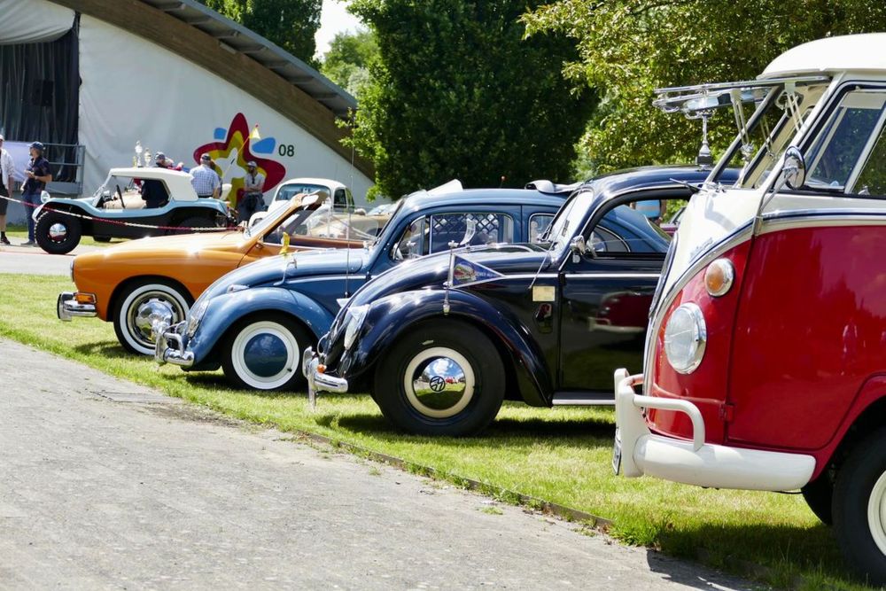 Historische Fahrzeuge des Typs VW stehen aufgereiht nebeneinander. Im Hintergrund ist die Volksbank-Arena zu sehen.